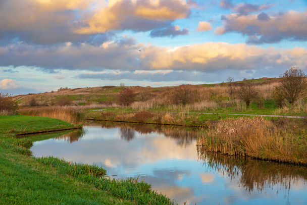 Hermoso paisaje con colinas, agua y puesta de sol en Buytenpark, Zoetermeer, Países Bajos - Foto, Imagen