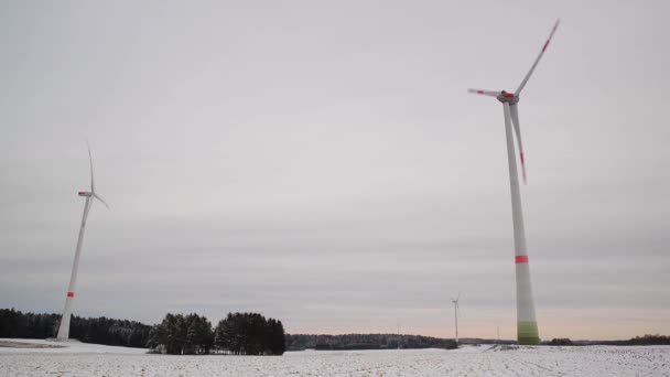 Alacsony szögű felvétel egy szélfarmról a téli tájban. Széles látószögű forgó szélturbinák egy havas mezőn Németországban. - Felvétel, videó