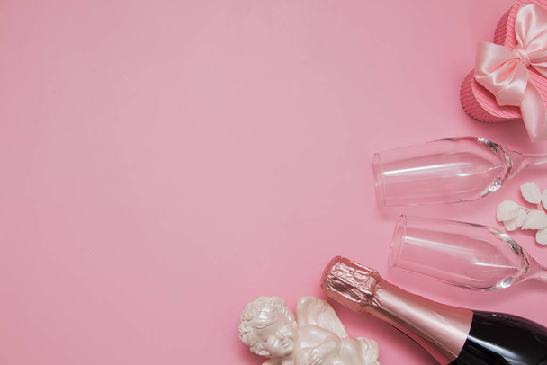 Макет с шампанским, бокалами, ангелом и подарком на розовом фоне с копировальным местом на День Святого Валентина или свадьбу - Фото, изображение