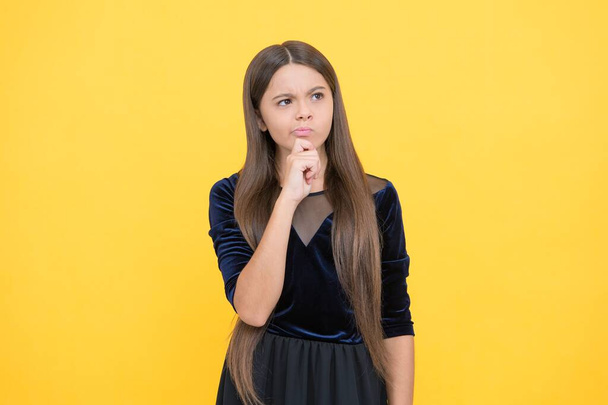 thoughtful girl child with long hair on yellow background, decision - Foto, afbeelding