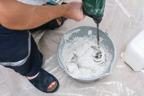 A male worker spreads the putty mixture and flattens wall. - Foto, Bild