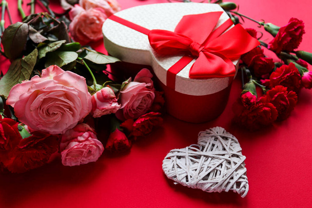 Beautiful Valentines Day greeting card. Decorative heart, gift box heart-shaped and flowers on red background close-up - Fotografie, Obrázek