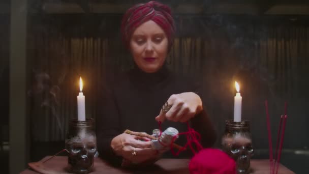 Senior Hexe Wahrsagerin verwendet Voodoo-Puppe und rotes Seil zu schrecklichen magischen Ritual - Filmmaterial, Video