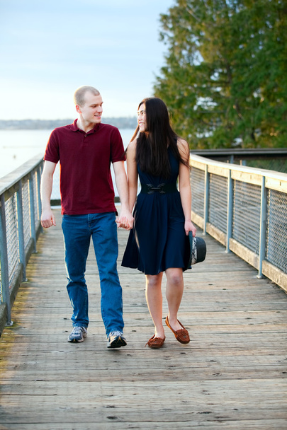 ラで木製の桟橋に一緒に歩いて若い異人種間のカップル - 写真・画像