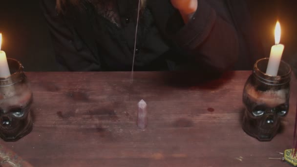 Молодая ведьма-гадалка вращает круглый кристалл иглы на столе в мистическом ритуале - Кадры, видео