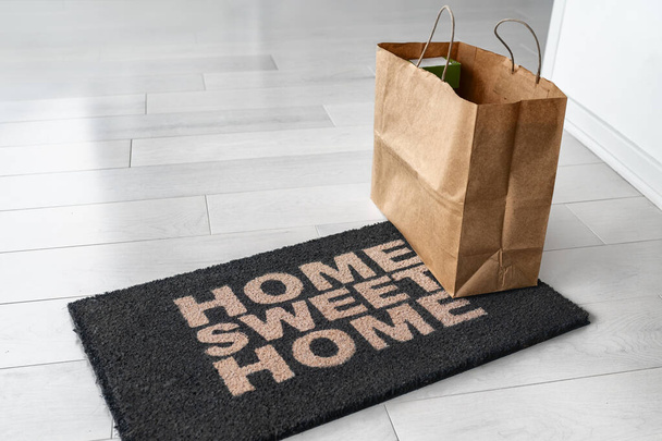 Home delivery of food grocery bag left at door entrance mat for Corona virus prevention safety. Precaution measures against COVID-19, paper shopping bag delivered without contact - Foto, Imagen