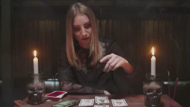 Young witch female fortune teller uses tarot card, dices and phone to read future - Footage, Video