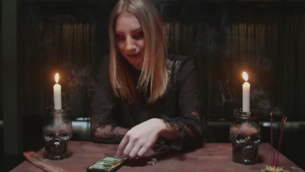 Young witch female fortune teller uses dices and phone to read future - Footage, Video