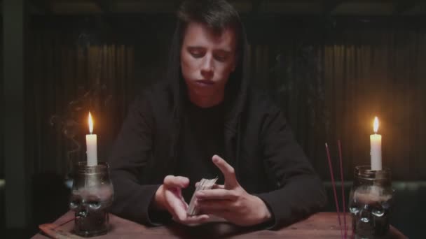 Skoncentrowany tajemniczy czarodziej męski wróżbita tasować karty i przygotować je do przyszłego opowiadania - Materiał filmowy, wideo