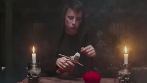 Concentrato misterioso mago indovino maschio utilizza bambola voodoo e corda rossa per terribile rituale magico - Filmati, video