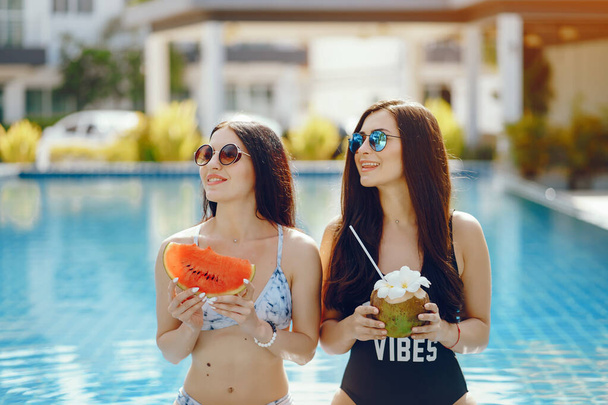 two girls having fruit by the pool - Photo, Image