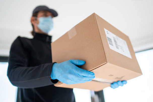 Home delivery shopping box man wearing gloves and protective mask delivering packages at door - Foto, immagini