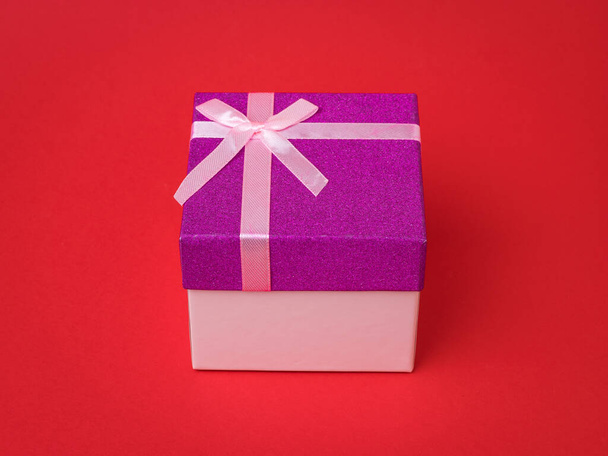 Stylish gift box with a bow on a red background. A holiday gift. - Zdjęcie, obraz