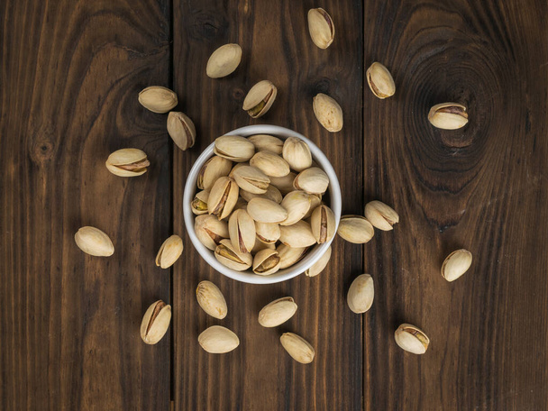 Top näkymä keraaminen kulho hajallaan pistaasipähkinöitä. Luonnollinen proteiinin ja hiilihydraattien lähde. - Valokuva, kuva
