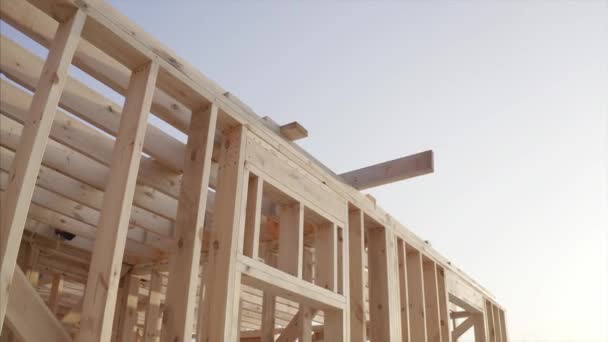 οικοδόμοι που εργάζονται σε ημιτελές εσωτερικό σπίτι πλαίσιο με ξύλινα δοκάρια της οροφής και τοίχους με μπλε ουρανό στο παρασκήνιο - Πλάνα, βίντεο