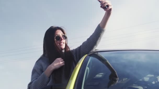 Young woman with sunglasses leaned out of the car window and records self video selfie stories - Footage, Video