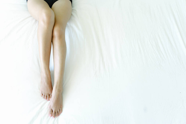 Closeup woman legs on white bed with over light form window, beauty and skin care concept, selective focus - Foto, Bild