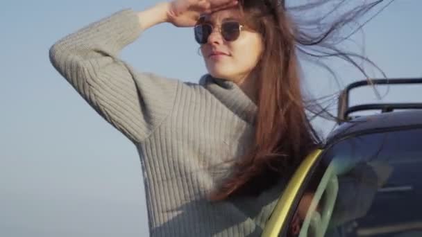Young beautiful woman with long hear leaned out of the car window - Footage, Video