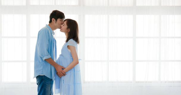 happy asian husband kiss his pregnant wife at home - Foto, afbeelding
