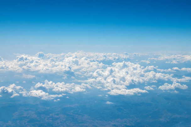 Blauer Himmel mit großen, schönen Wolken und ein Blick von oben auf die Erde an einem strahlend sonnigen Tag aus dem Fenster eines fliegenden Flugzeugs. Sky-Ersatzvorlage - Foto, Bild