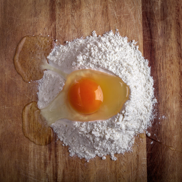 Розбите яйце в борошні на обробній дошці
 - Фото, зображення