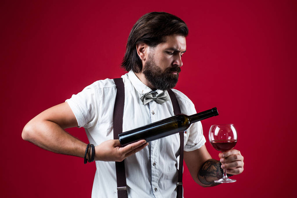 silled waiter. stylish male barman. drinking wine glass. bearded man in suspenders drink red wine. elegant businessman wear bow tie for formal event. sommelier tasting alcohol. bartender - Fotó, kép