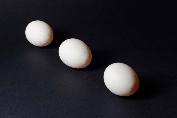 Three white eggs on a black background, dietary and healthy food rich in protein 2021 - 写真・画像