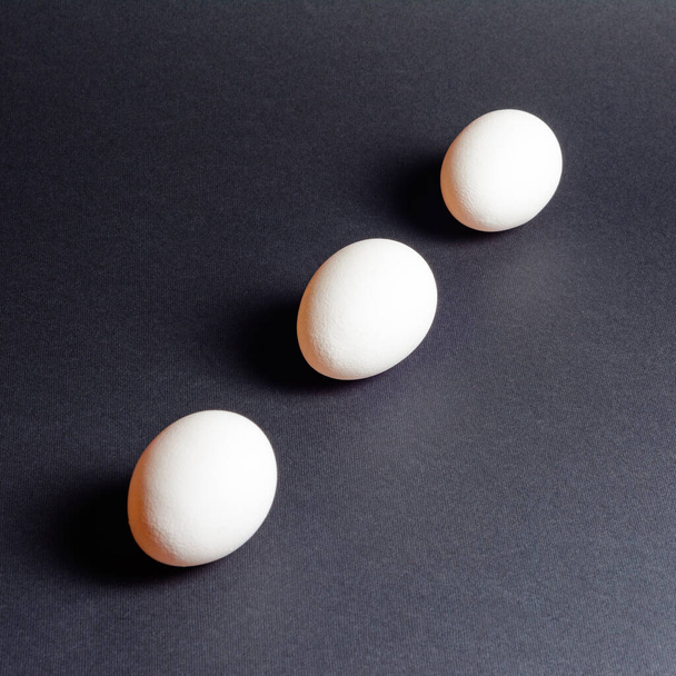 Three white eggs on a black background, dietary and healthy food rich in protein 2021 - Foto, Bild