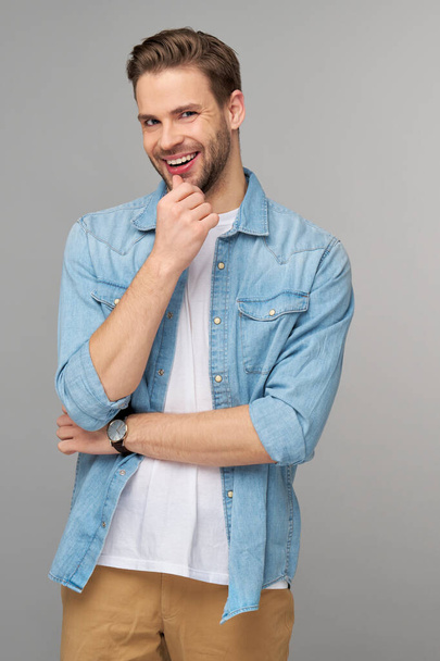 Portrait of young handsome caucasian man in jeans shirt over light background - Fotó, kép