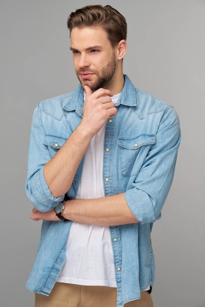 Portrait of young handsome caucasian man in jeans shirt over light background - Photo, Image