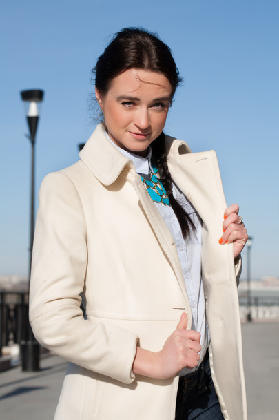 Girl in a white coat on the sky background - Photo, Image