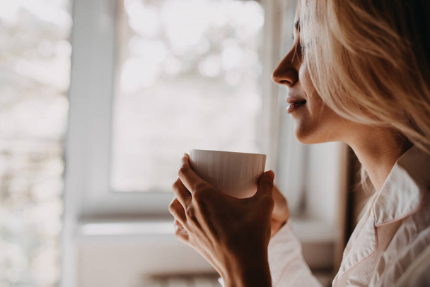 gyönyörű fiatal nő iszik kávét az ágyban reggel - Fotó, kép
