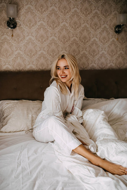 beautiful young woman in pajamas relaxing in bed in morning - Photo, image