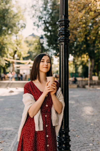 retrato de hermosa mujer joven con taza de papel de café en la calle - Foto, imagen