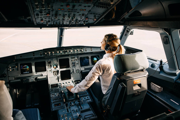 portrait of beautiful blonde pilot sitting inside of airplane - Photo, image
