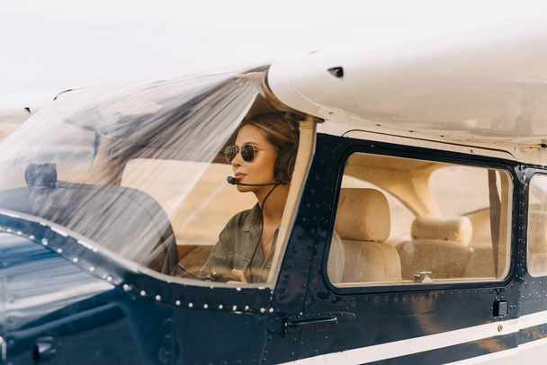 портрет красивой блондинки пилота, сидящего внутри самолета - Фото, изображение