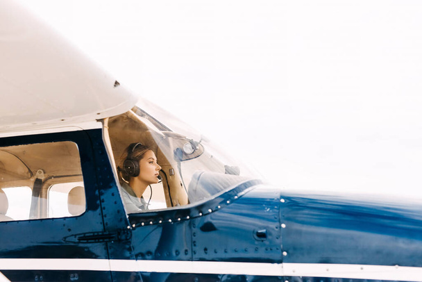 portrait of beautiful blonde pilot sitting inside of airplane - Фото, изображение