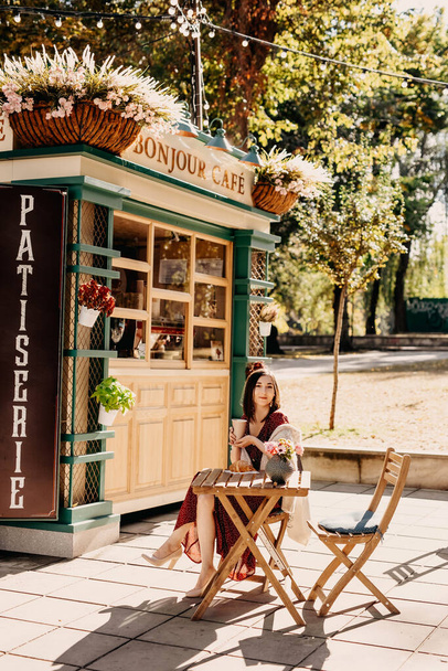 portrét krásné mladé ženy sedící v pouliční kavárně s papírovým kelímkem horkého nápoje a croissant - Fotografie, Obrázek