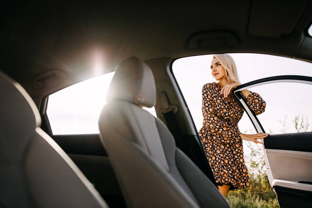 kaunis nuori nainen seisoo auton ulkopuolella ja nojaa oveen - Valokuva, kuva