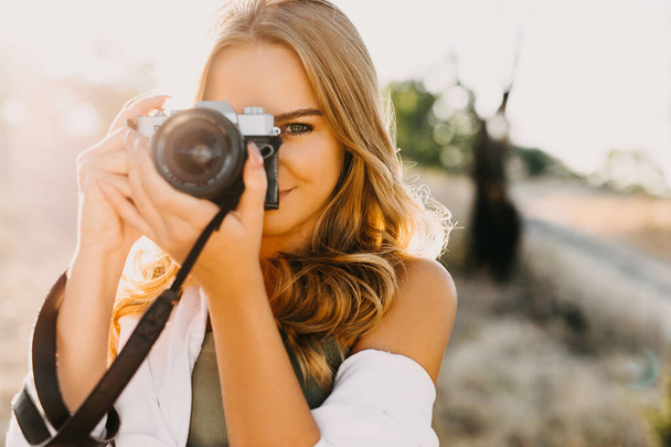 portrait of beautiful young female photographer with vintage camera on nature - Zdjęcie, obraz