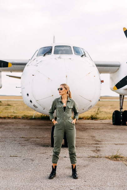 portrait of beautiful blonde pilot woman in front of airplane - Photo, image