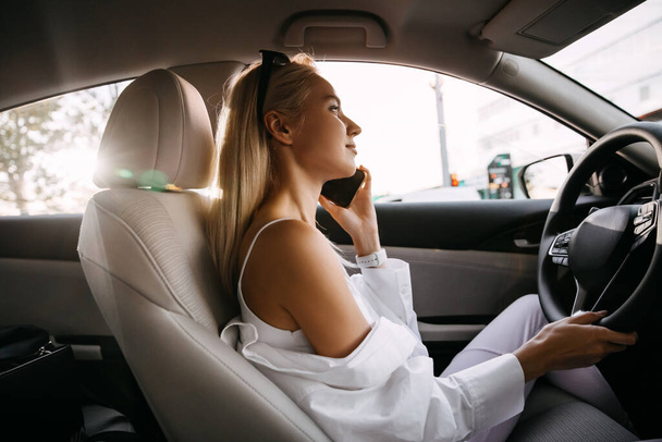 piękna młoda kobieta prowadzi samochód i rozmawia przez telefon - Zdjęcie, obraz