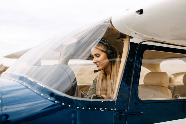 πορτρέτο του όμορφου ξανθού πιλότου που κάθεται μέσα στο αεροπλάνο - Φωτογραφία, εικόνα