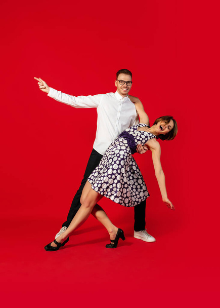 Old-school fashioned young couple dancing isolated on red background - Foto, immagini
