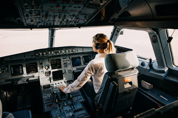 πορτρέτο του όμορφου ξανθού πιλότου που κάθεται μέσα στο αεροπλάνο - Φωτογραφία, εικόνα