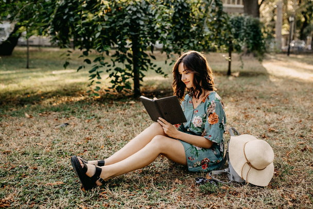 портрет красивої молодої жінки, що читає книгу на траві в парку
 - Фото, зображення