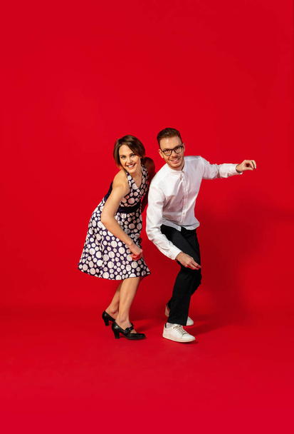 Old-school fashioned young couple dancing isolated on red background - Foto, Bild