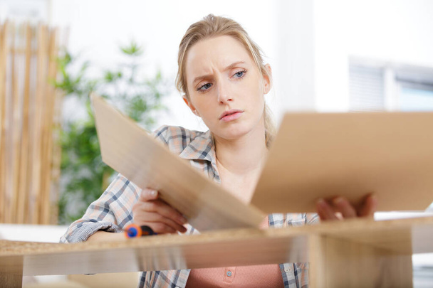 young woman frustrated fixing a furniture - Foto, Imagem