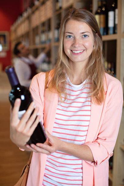 woman holding bottle of red wine in a store - Fotoğraf, Görsel