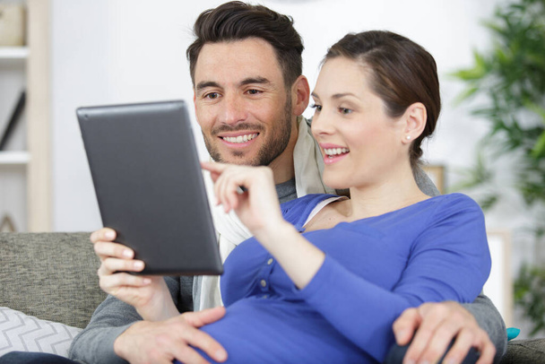 happy couple lying on bed and using digital tablet - Foto, Imagen